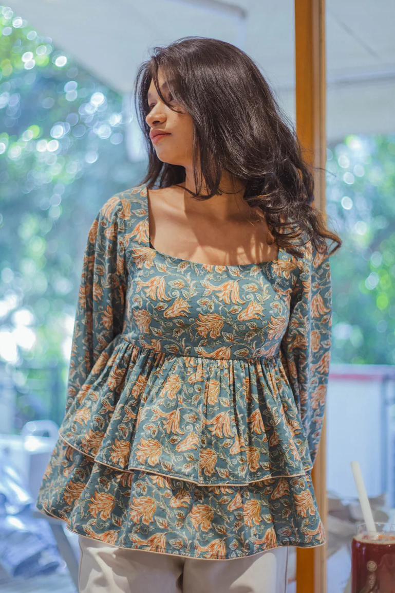 Woman wearing a floral print peplum tunic with a square neckline and tiered ruffles.